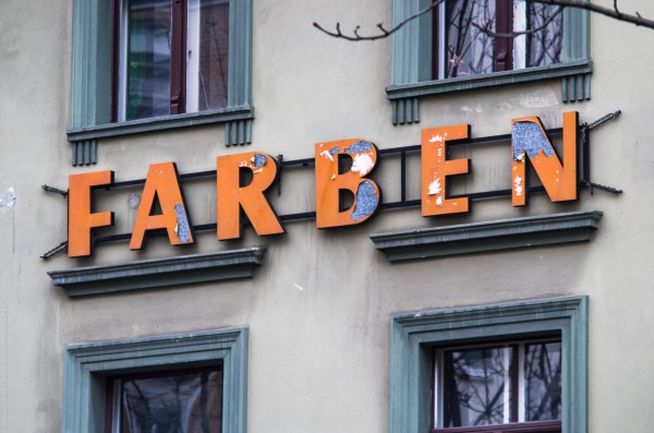 Hauswand mit Schriftzug "Farben", dessen Farben abblättern.