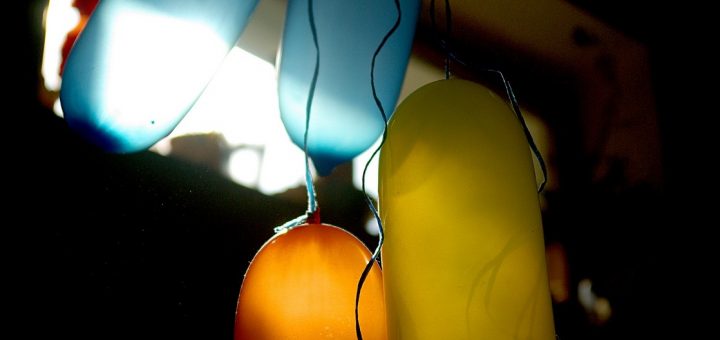 Blaue, gelbe und orange Luftballons im Gegenlicht